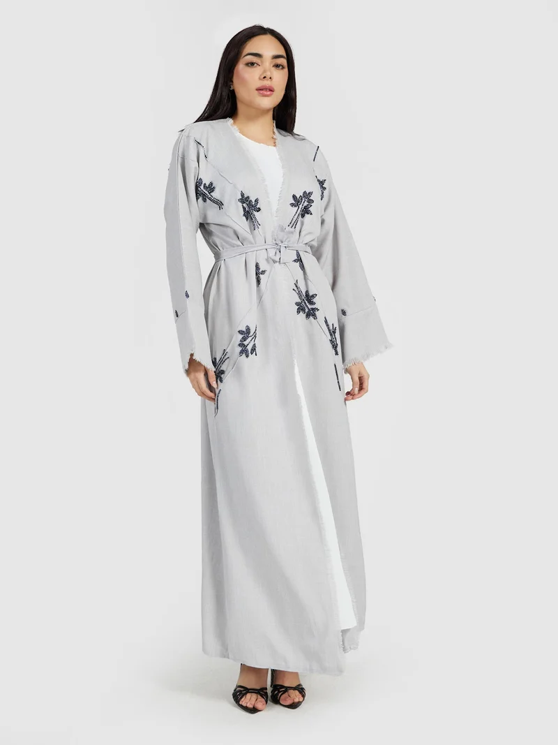 عباية رمادية بمظهر الكتان بتطريز زهري كحلي مزينة بشراشيب